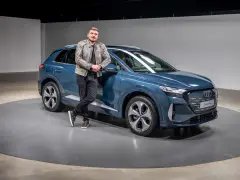 Ein Mann lehnt lässig an einem blauen Audi Q4 e-tron 2026.